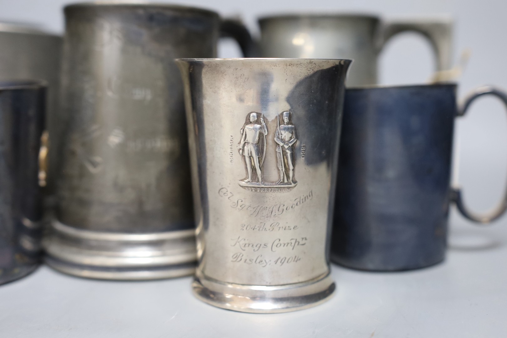 An Edwardian silver Kings company 204th prize Bisley 1904 commemorative beaker, 10cm and a collection of various pewter and plated shooting trophy mugs and tankards, Silver beaker 10 cms high.